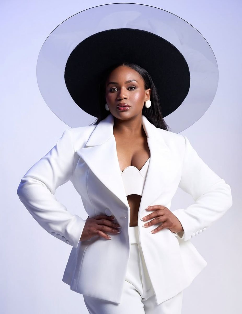 Jessica Divine in a white suit and a wide black hat